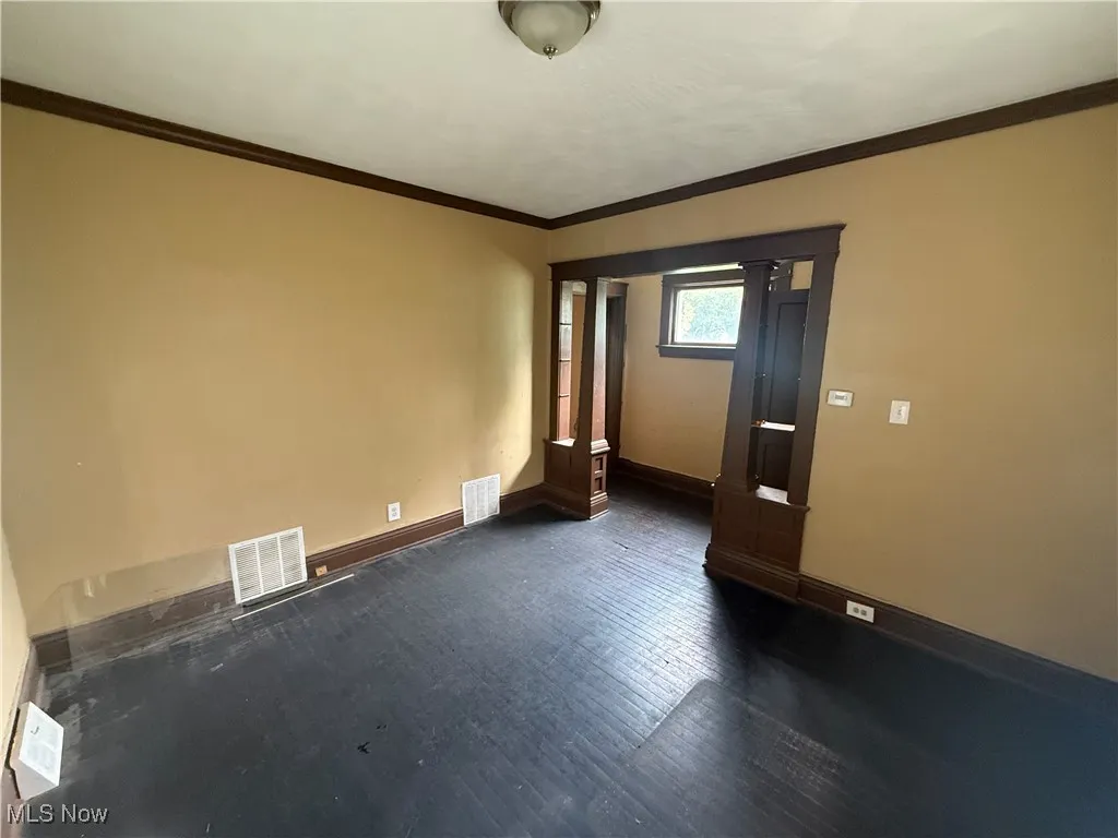 Unfurnished room with ornamental molding and dark wood-style flooring