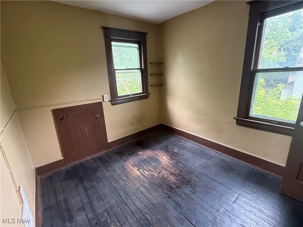 Spare room with dark wood-type flooring and baseboards