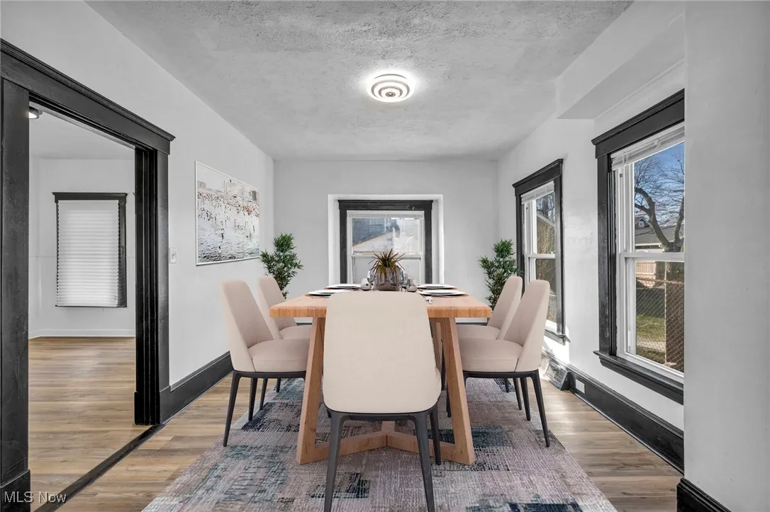 Dining space featuring a textured ceiling, wood finished floors, and baseboards