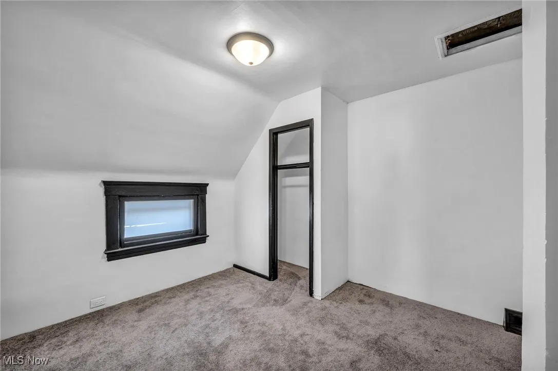 Additional living space with carpet floors and lofted ceiling