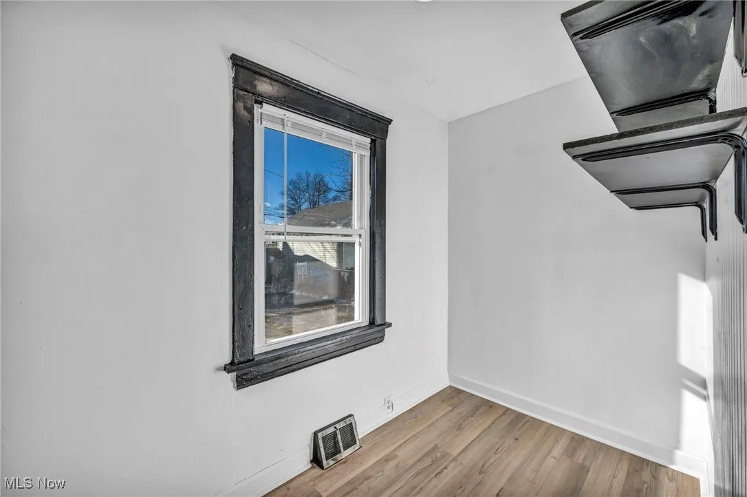 Empty room featuring visible vents, baseboards, and wood finished floors