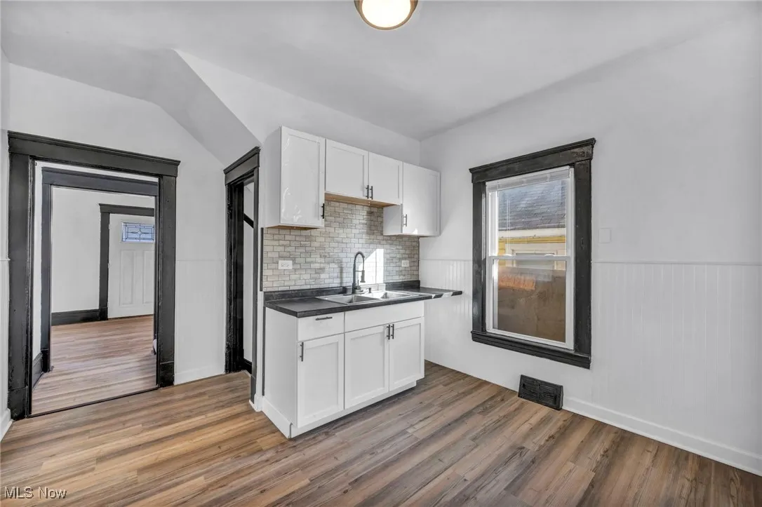 Kitchen featuring dark countertops, visible vents, white cabinets, and a sink