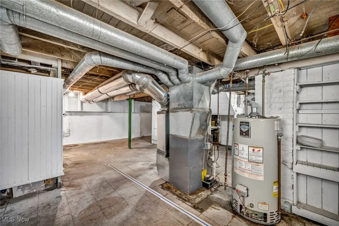 Unfinished basement featuring heating unit and gas water heater