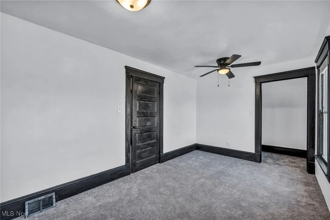 Spare room with carpet floors, baseboards, visible vents, and ceiling fan