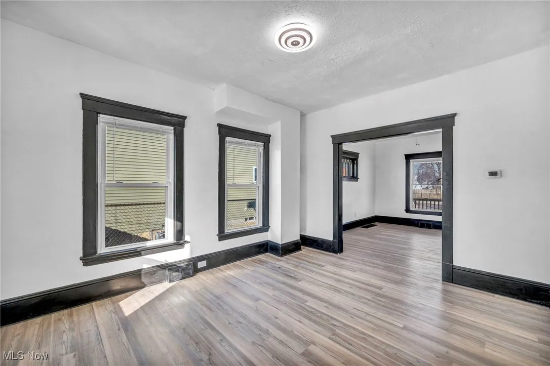 Unfurnished room featuring a textured ceiling, baseboards, and wood finished floors