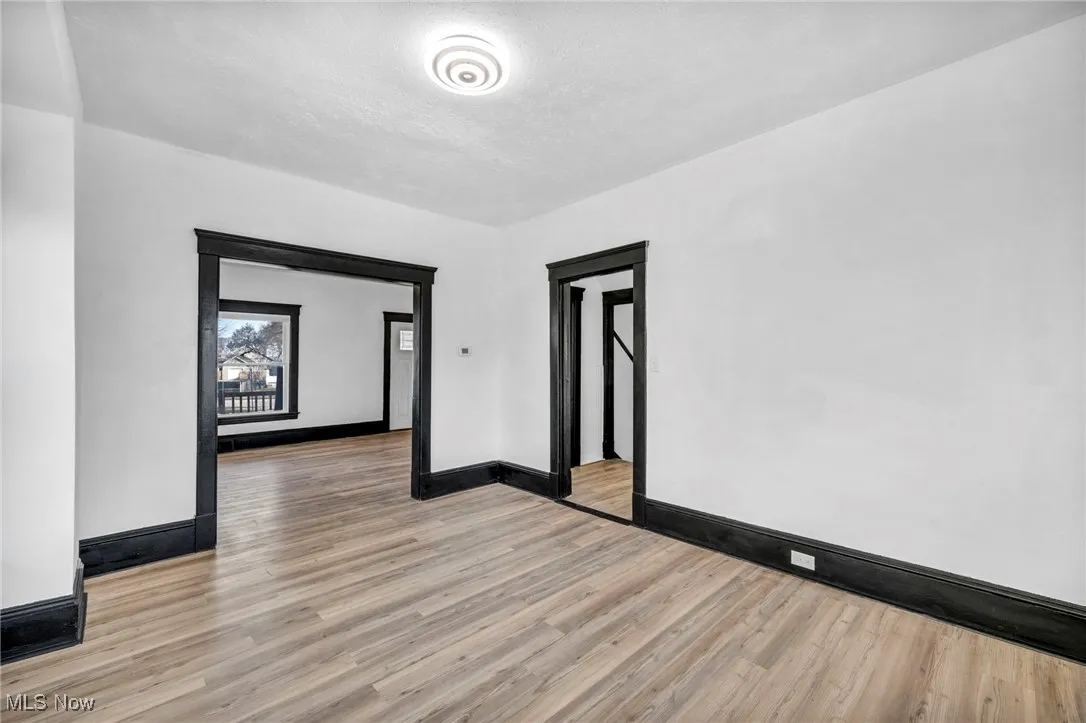 Unfurnished room with light wood-type flooring, baseboards, and a textured ceiling