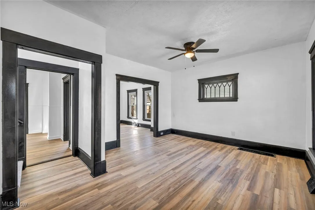 Empty room with visible vents, ceiling fan, light wood-style flooring, and baseboards