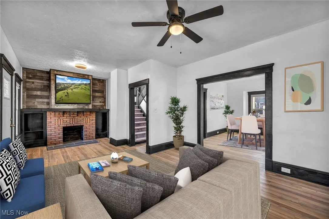 Living room featuring a textured ceiling, a fireplace, baseboards, and wood finished floors