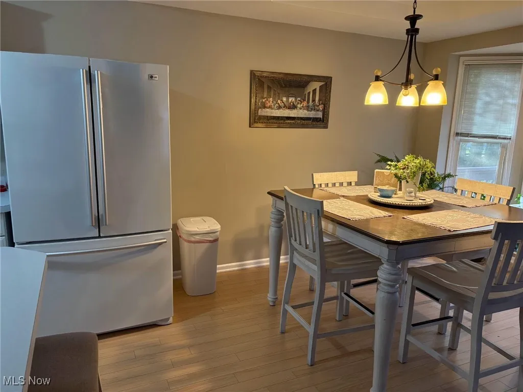 Dining area with light wood-type flooring, baseboards, and a notable chandelier