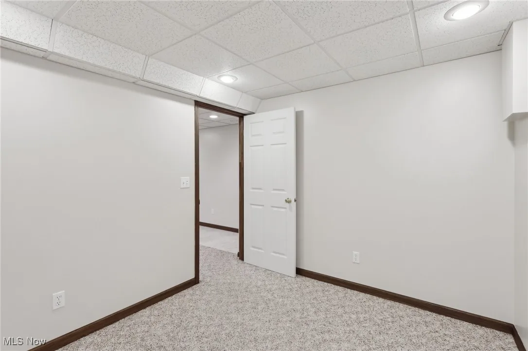 Finished below grade area with baseboards, a drop ceiling, carpet flooring, and recessed lighting