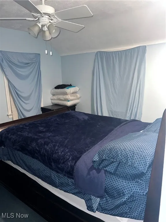 Carpeted bedroom with baseboards, ceiling fan, and a textured ceiling
