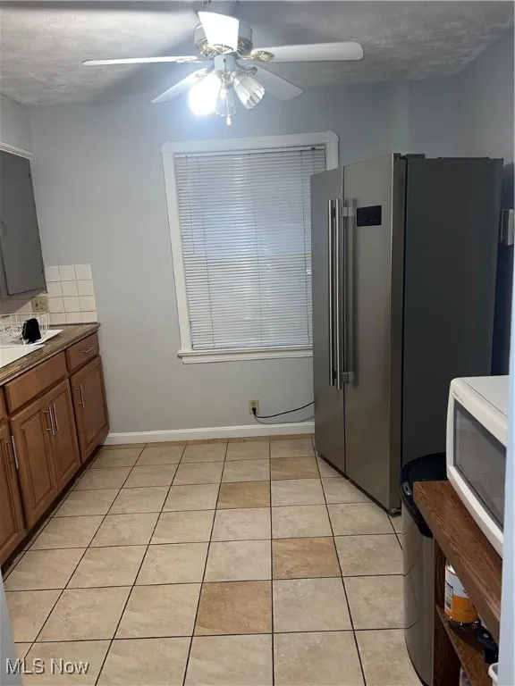 Kitchen featuring stove, light tile patterned flooring, a sink, dark countertops, and tasteful backsplash