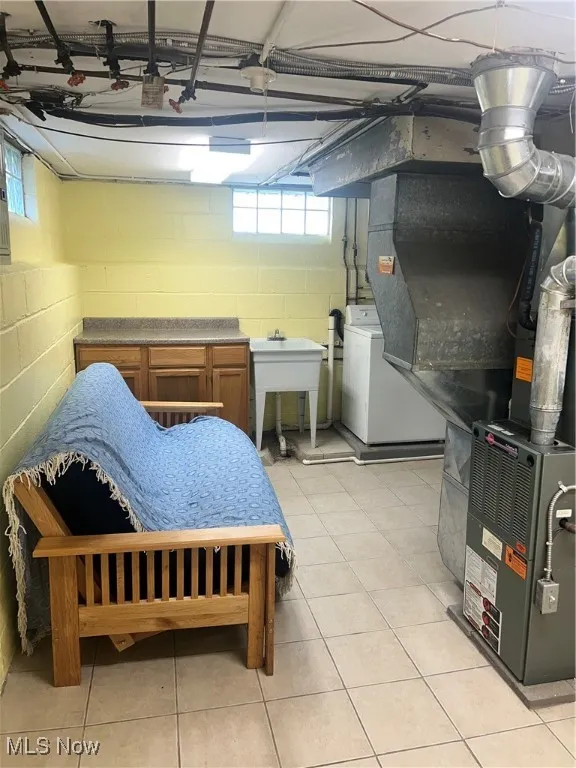 Basement with washer / dryer, concrete block wall, a sink, and light tile patterned floors