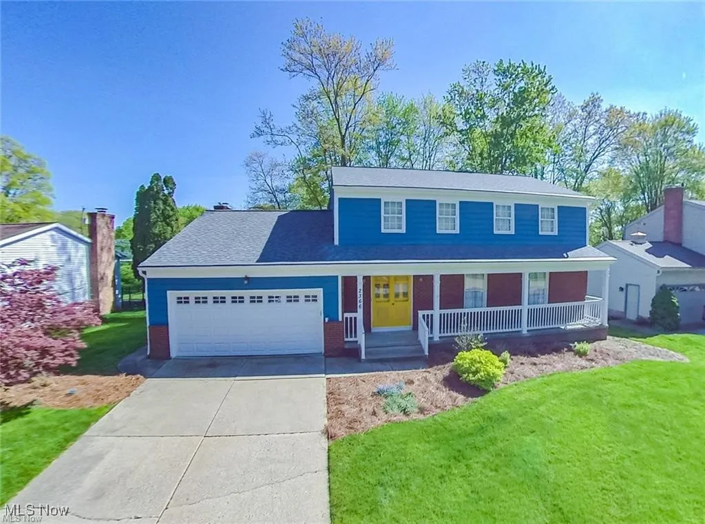 Traditional-style house with covered porch, driveway, a garage, and a front lawn