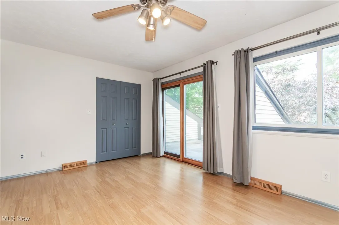 Spare room with light wood finished floors, healthy amount of natural light, and ceiling fan