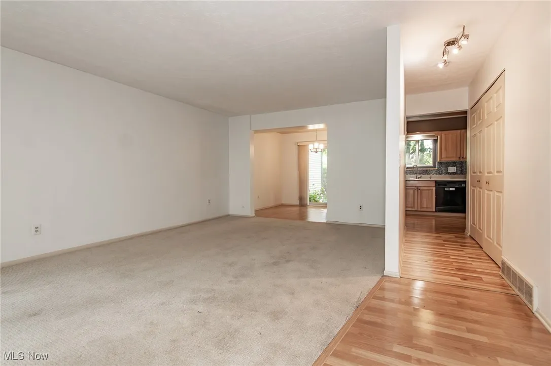 Unfurnished living room featuring a chandelier, light wood-style floors, and light carpet