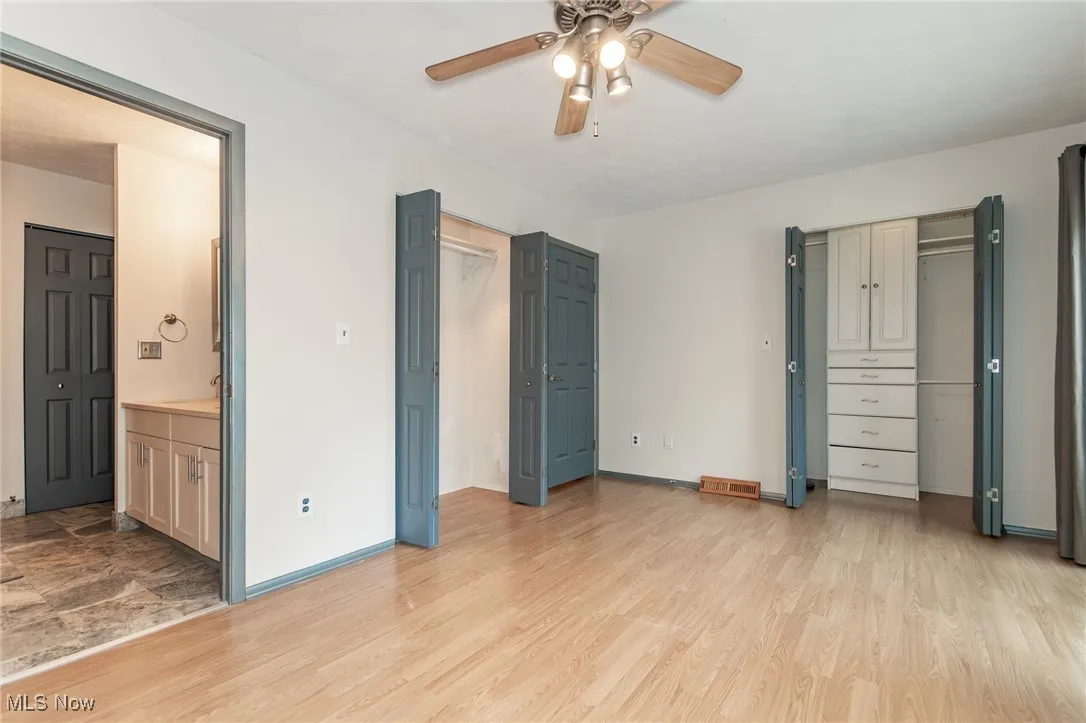 Unfurnished bedroom featuring light wood-style flooring, ensuite bath, and a ceiling fan