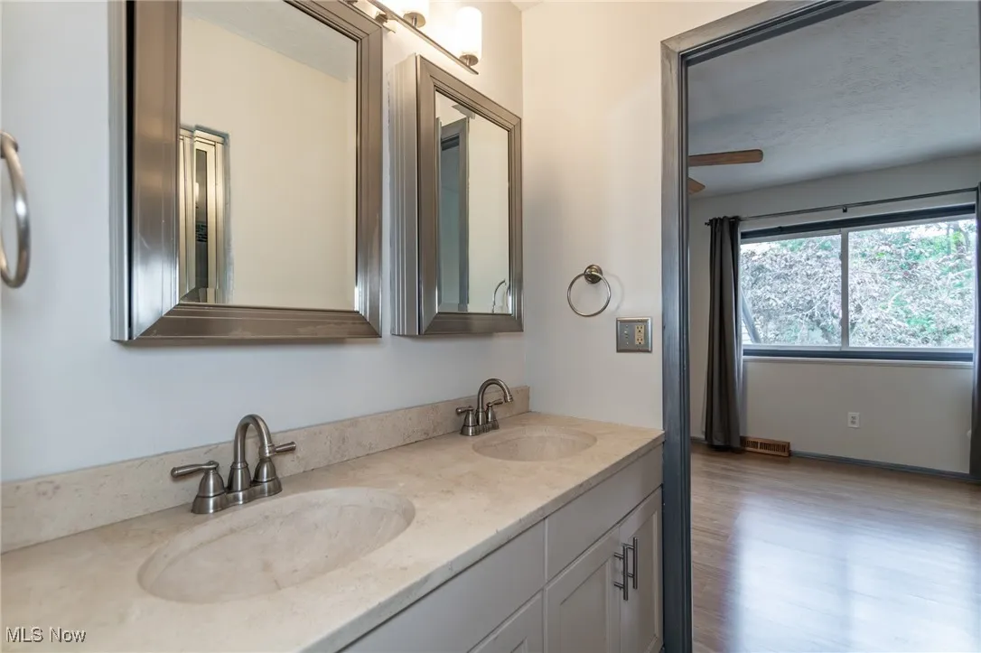 Full bath featuring double vanity and wood finished floors