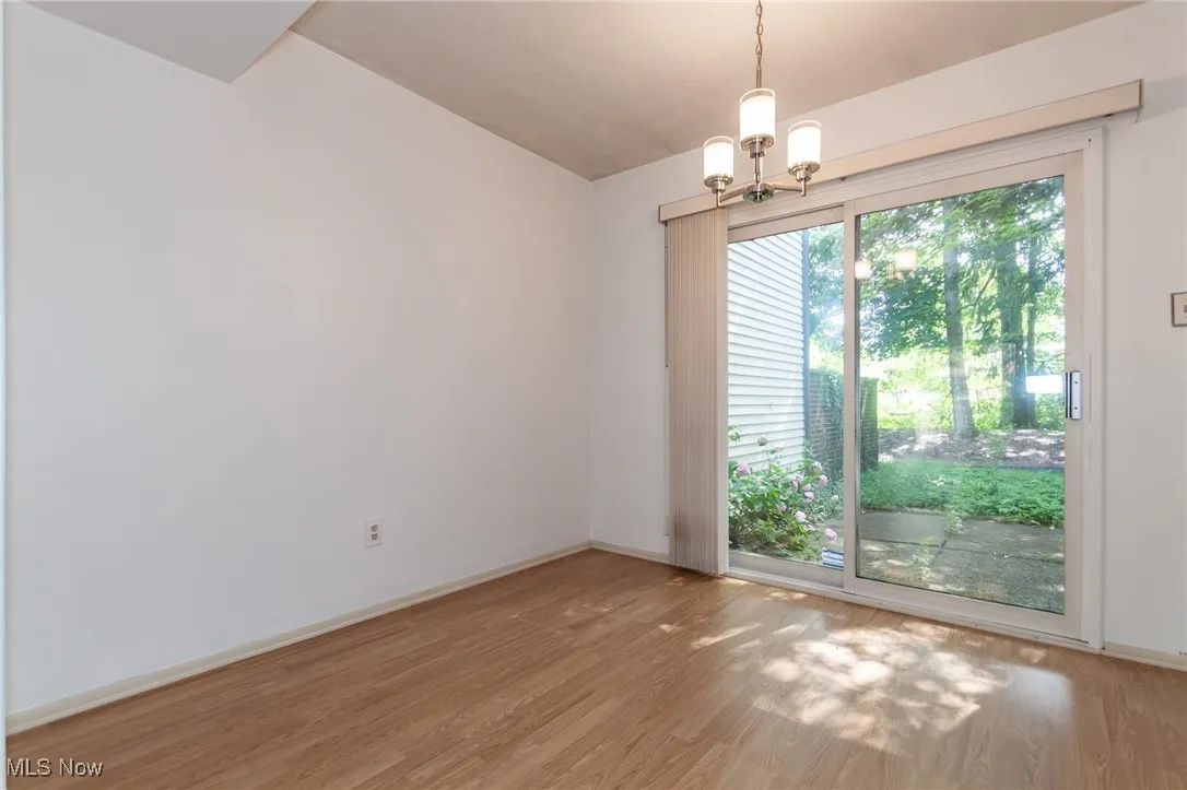 Spare room with wood finished floors and a chandelier