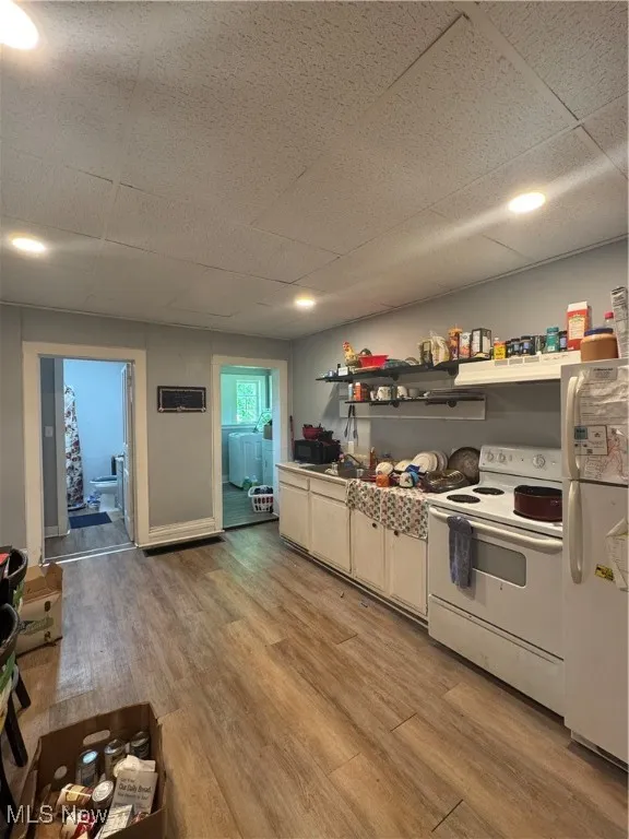 Kitchen with refrigerator, range, light wood finished floors, and a paneled ceiling