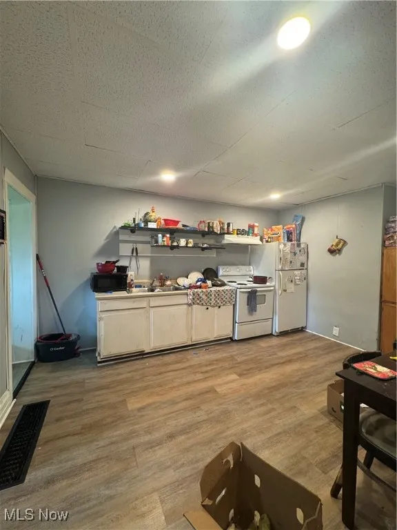 Kitchen with stove, refrigerator, light wood-type flooring, and a drop ceiling
