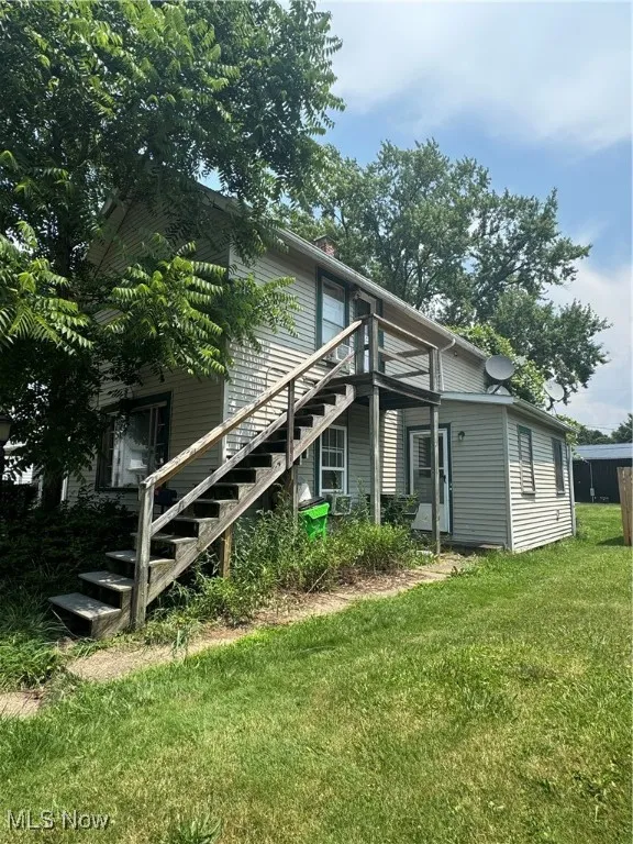 View of side of home featuring stairway and a yard