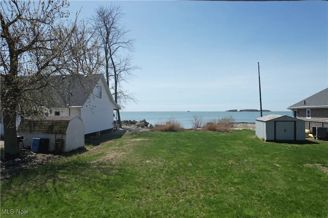 View of yard with an outdoor structure, a water view, and a shed