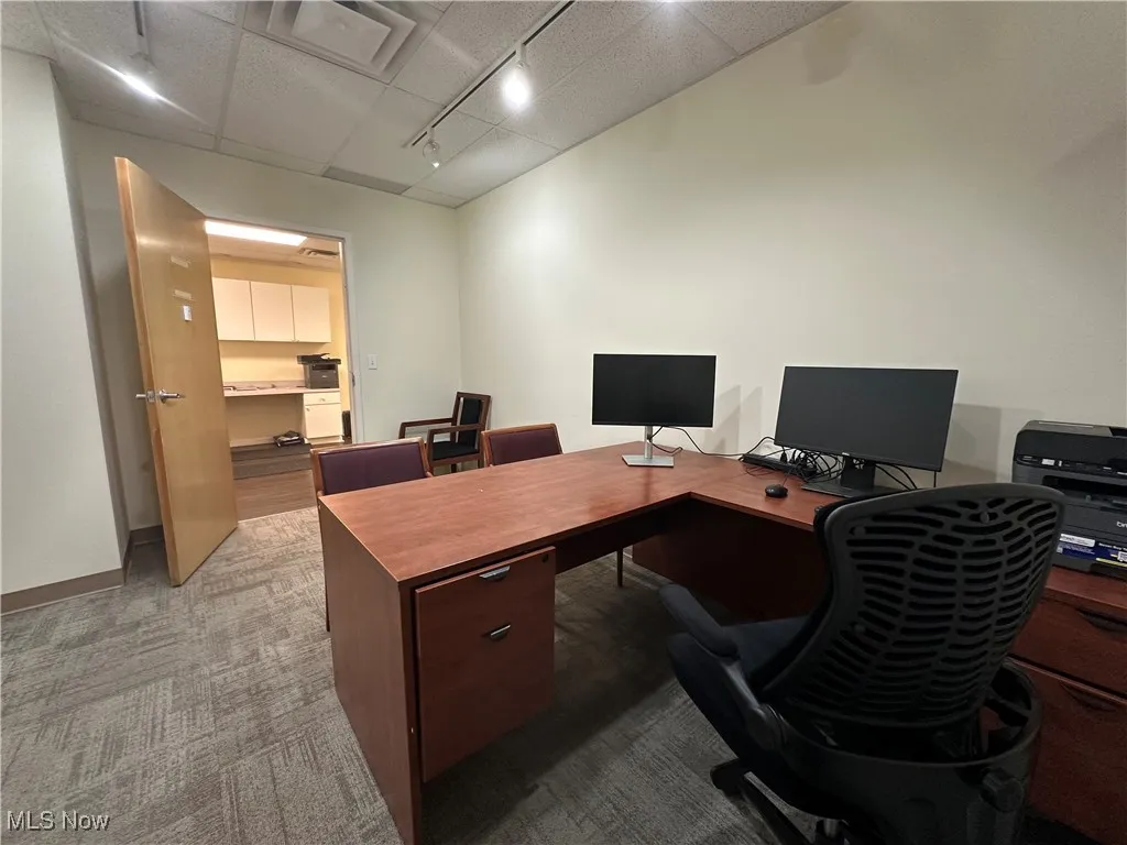 Carpeted office with track lighting and baseboards