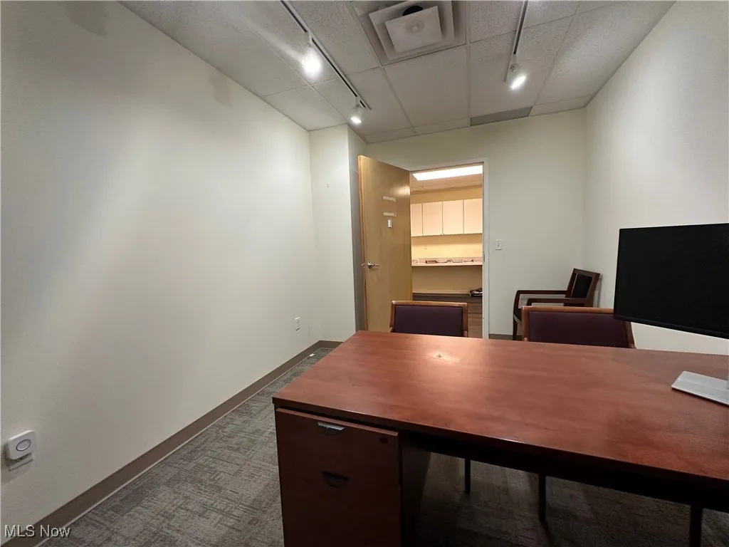 Office space with rail lighting, dark colored carpet, and baseboards