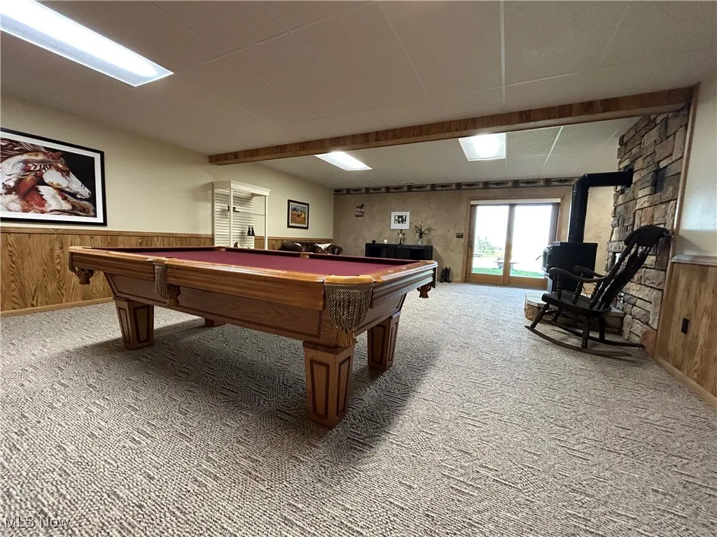Playroom with a wood stove, wood walls, pool table, and carpet floors