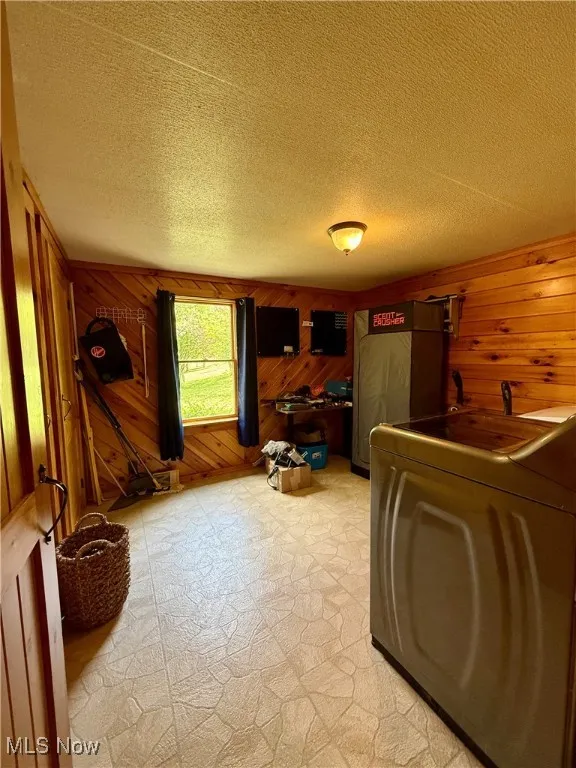 Living room with washer / dryer, wooden walls, and a textured ceiling