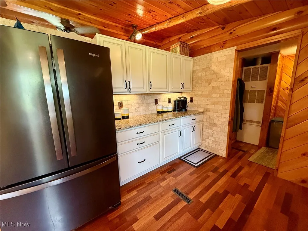 Kitchen featuring freestanding refrigerator, wooden ceiling, dark wood finished floors, white cabinetry, and a heating unit