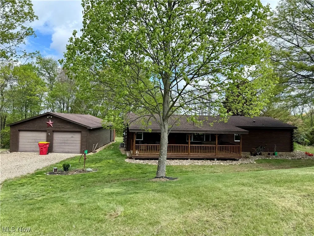 View of front of home featuring an outbuilding, a front lawn, a detached garage, and log siding