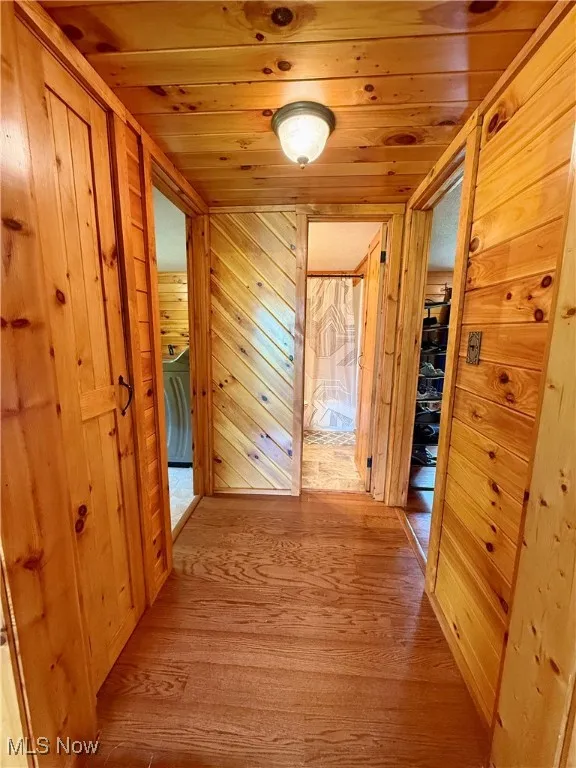 Corridor featuring wood finished floors, wood ceiling, and wooden walls