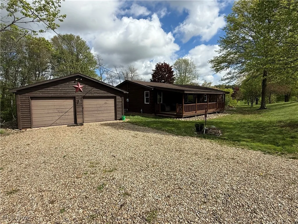 View of front of property featuring driveway, a front yard, an outbuilding, and a porch