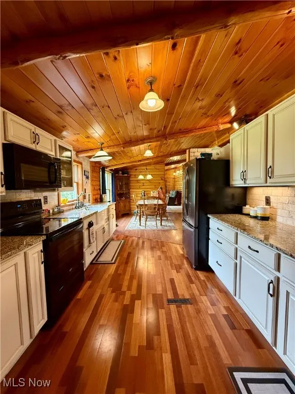 Kitchen with black appliances, wooden ceiling, white cabinets, wood finished floors, and decorative backsplash
