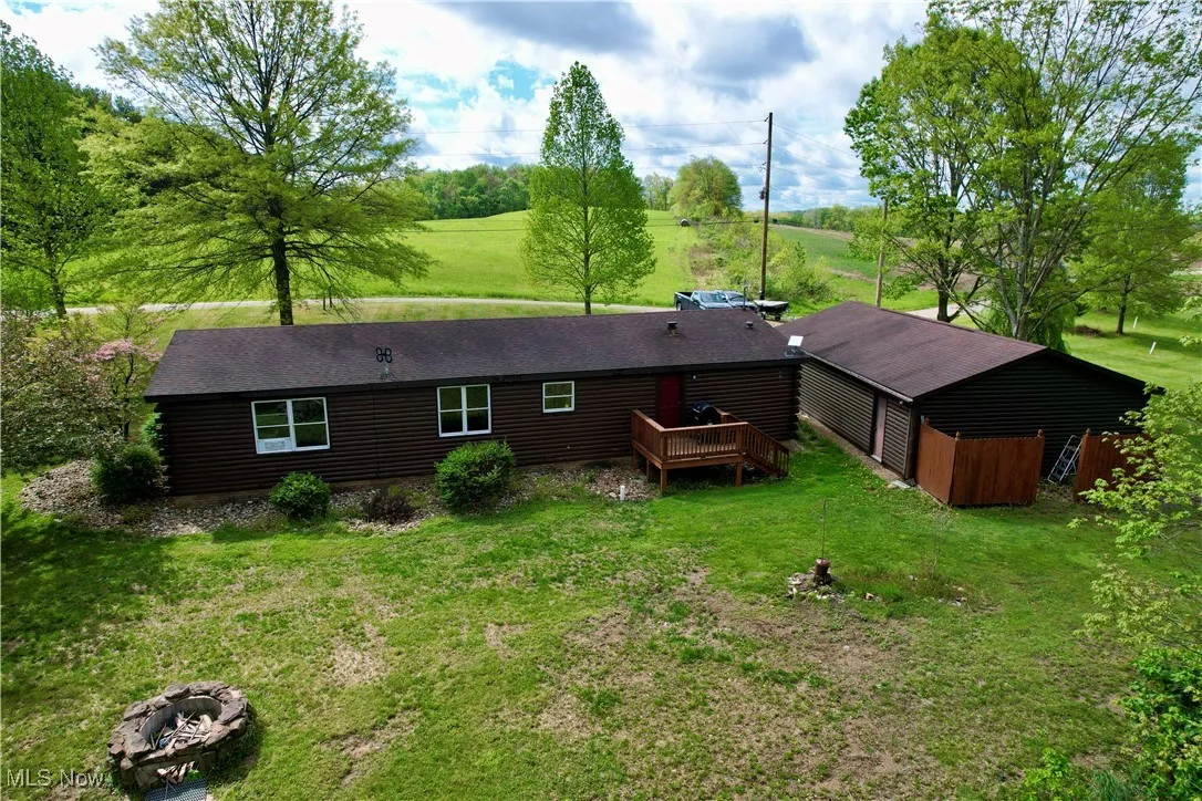 Rear view of property featuring a yard, a wooden deck, and a shingled roof