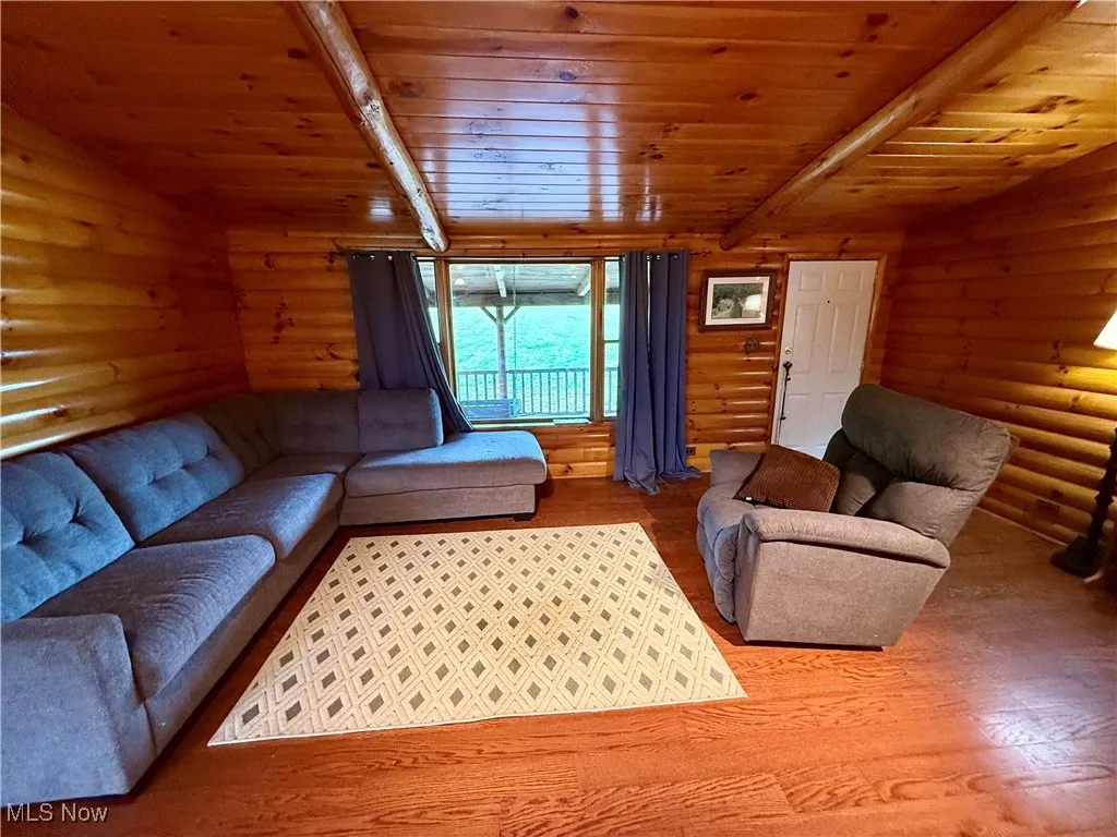 Living room featuring wood finished floors, wood ceiling, beamed ceiling, and log walls
