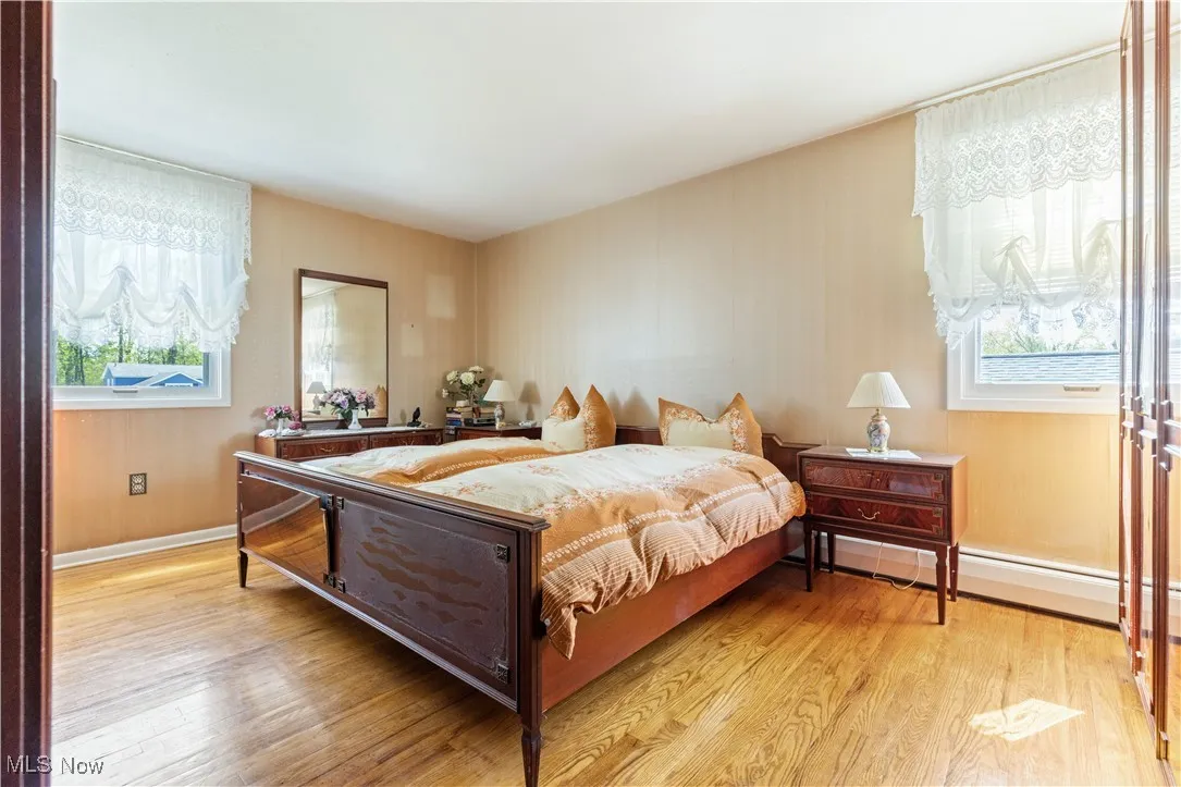 Bedroom featuring light wood-style floors, baseboards, and multiple windows