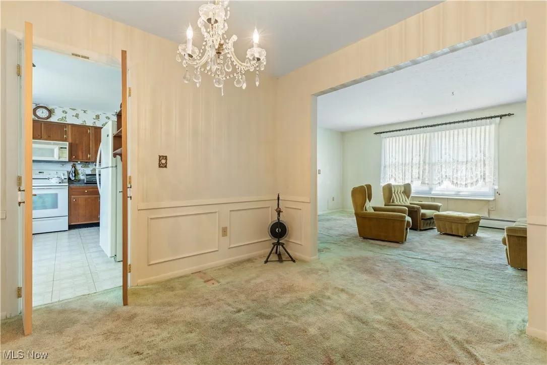 Sitting room featuring carpet flooring, an inviting chandelier, a decorative wall, and a baseboard radiator