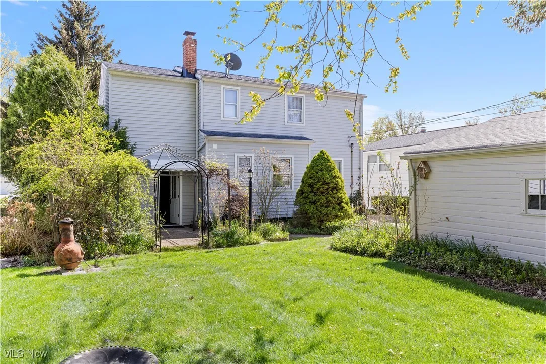 Rear view of property with a chimney and a yard
