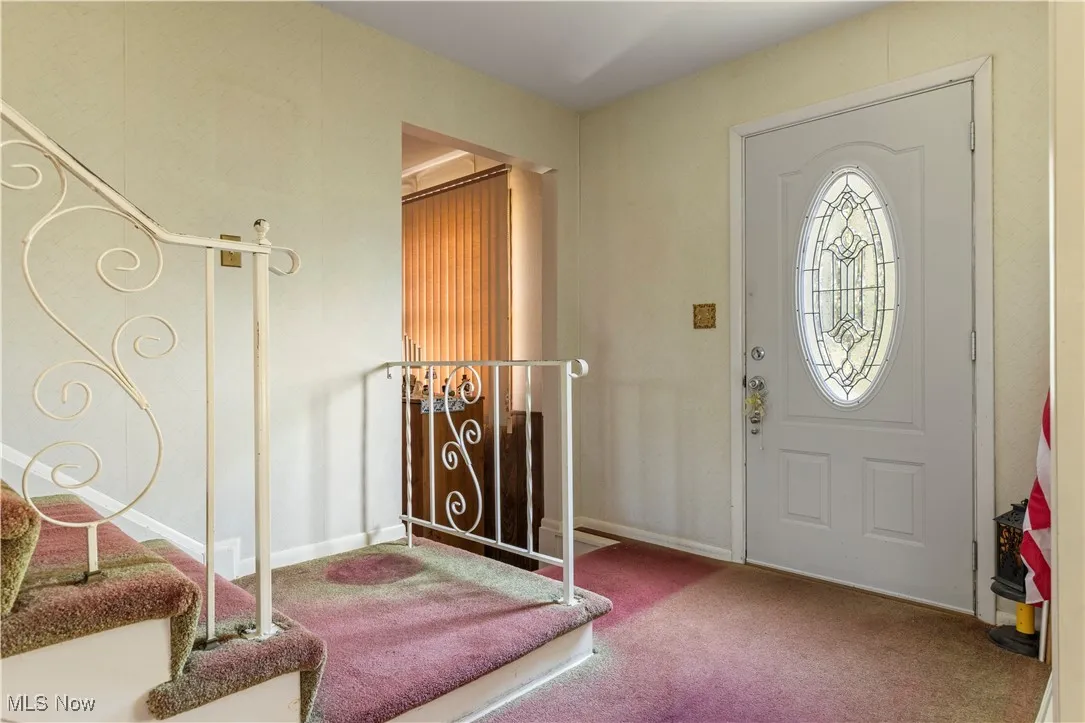 Carpeted foyer featuring baseboards