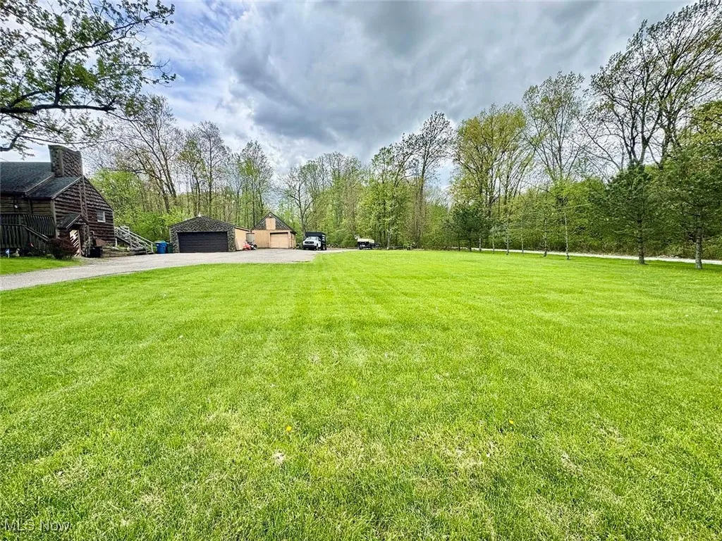 View of green lawn featuring driveway and a garage