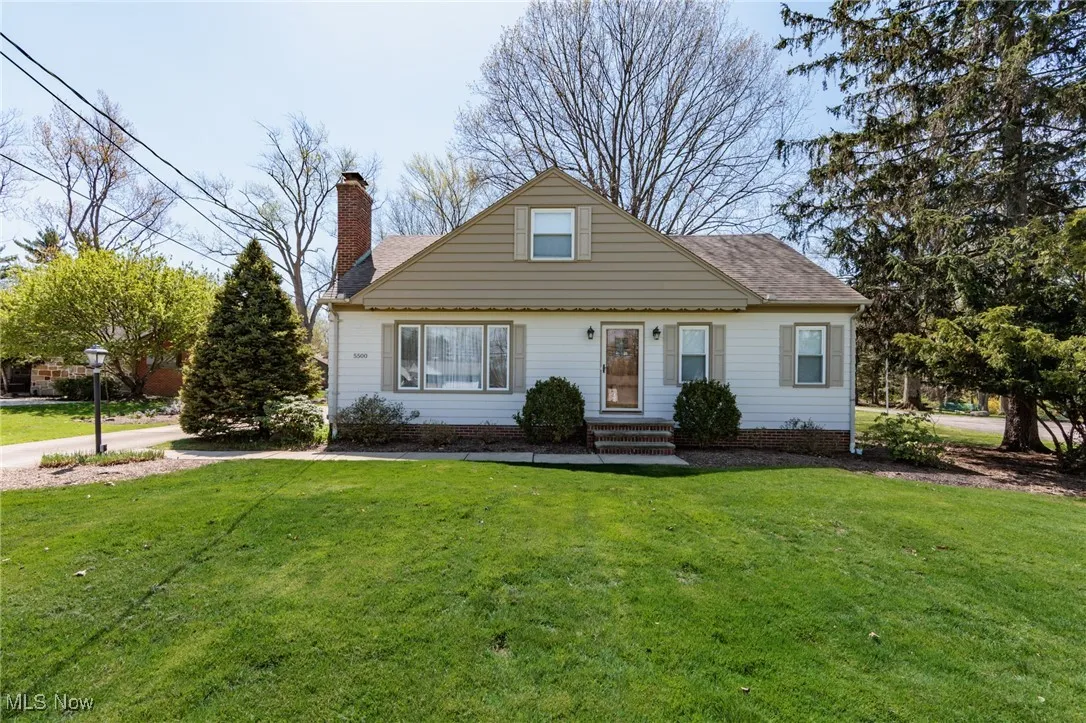View of front of house with roof with shingles, a chimney, and a front yard