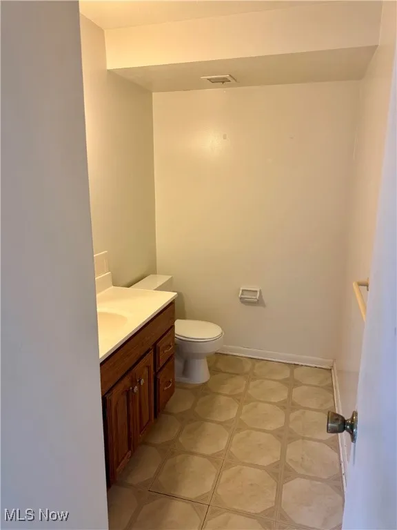 Half bath with toilet, vanity, and tile patterned floors