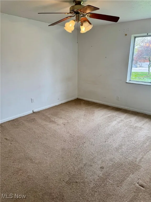 Unfurnished room with ceiling fan, carpet flooring, and baseboards