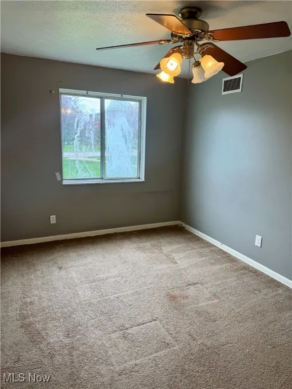 Spare room featuring carpet, baseboards, and a ceiling fan