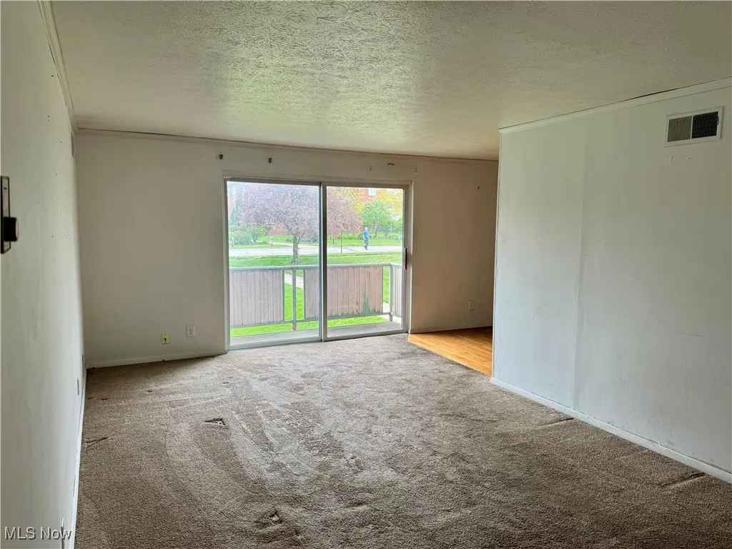 Empty room with carpet floors and a textured ceiling
