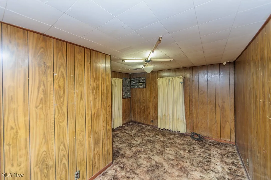 Carpeted empty room with wooden walls and ceiling fan
