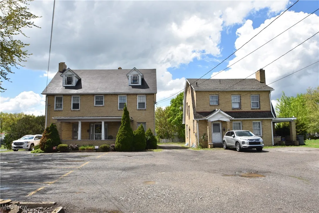 Colonial house with brick siding, uncovered parking, a chimney, and covered porch